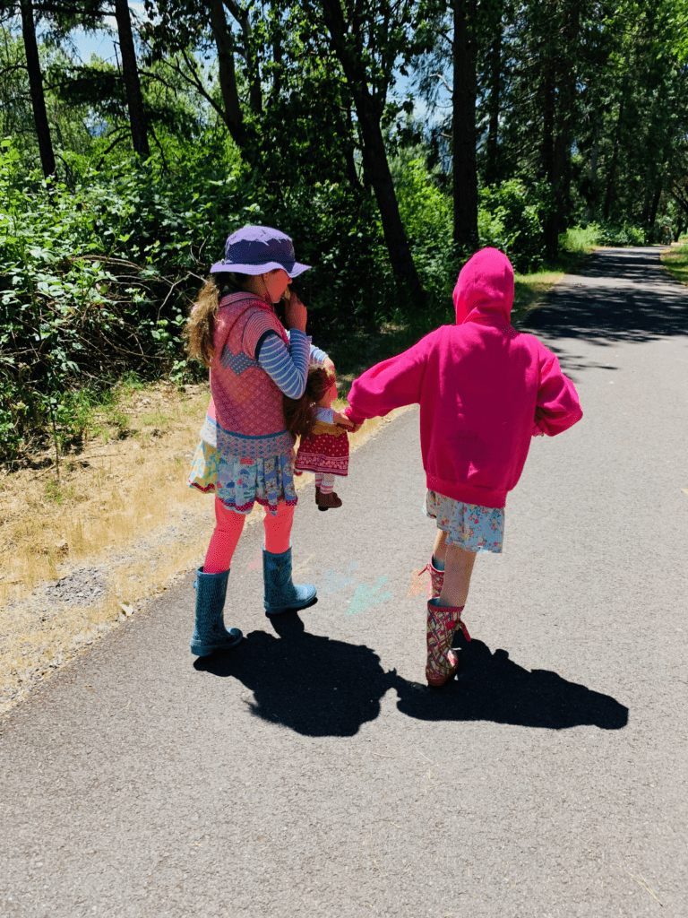 Our sweet girls on hike with their dolls in LL Bean rain boots with trees in the background