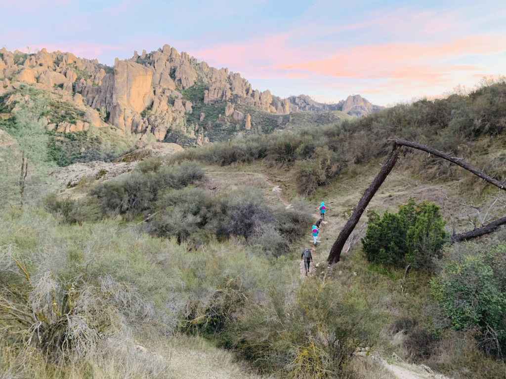 Family hiking down a trail into sunset at Pinnacles National Park