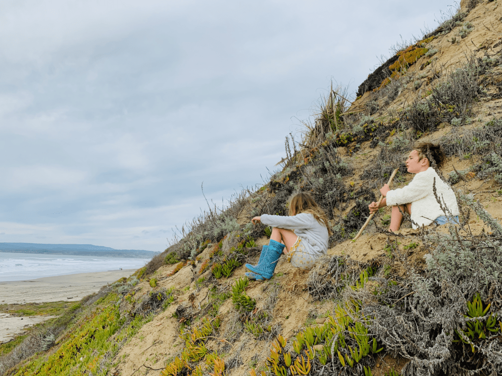 Kids climbing the sand dunes with LL Bean Boots and singing at La Selva State Beach with the ocean in the background