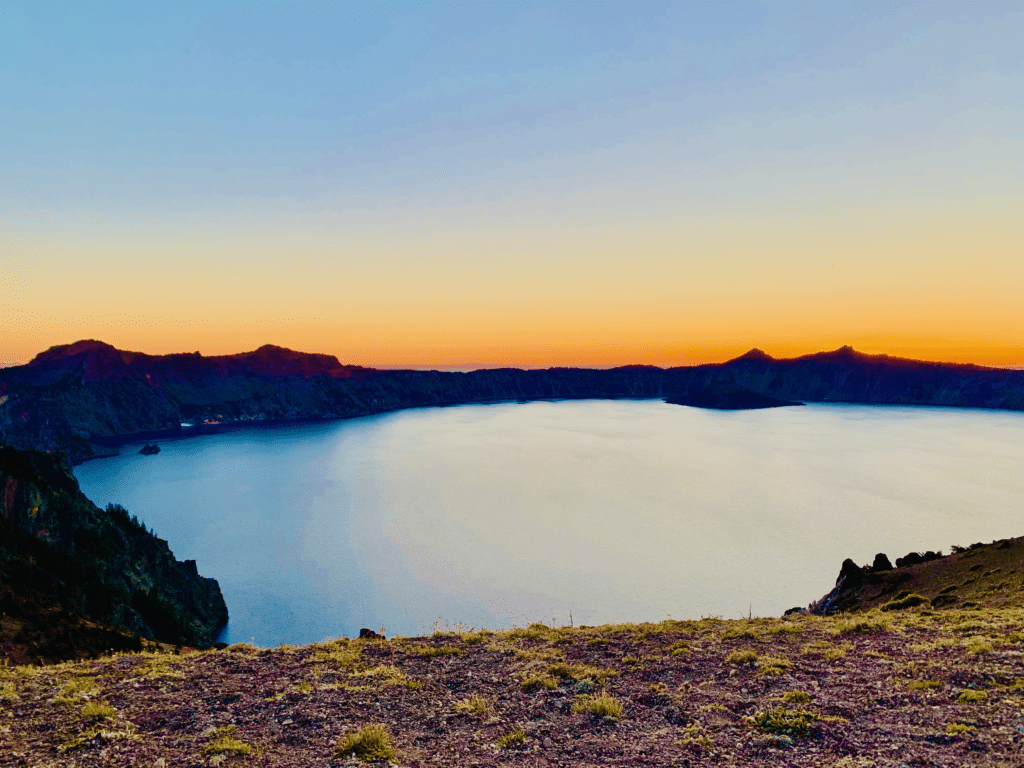 Crater Lake ethereal deep blue waters with a rainbow sunset with Wizard Island and Phantom Ship full panoramic view