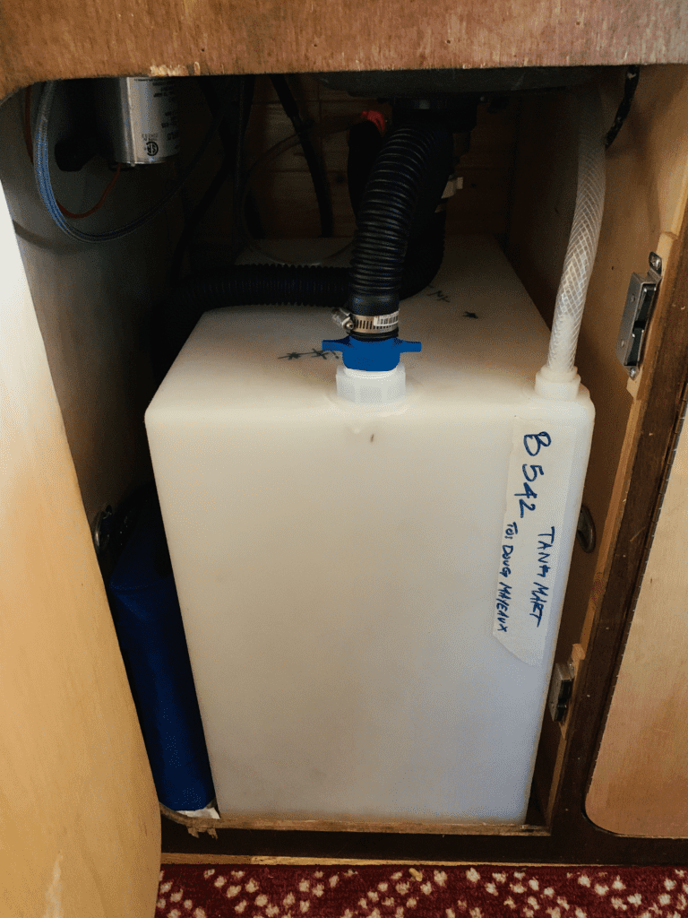 Self-installed van freshwater tank from Tank-Mart under the van kitchen sink with wooden van finishing in background