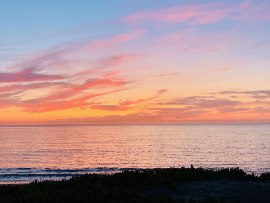 Half Moon Bay State Beach our van family part time home on a spectacular pink orange sunset with calm waves in the background