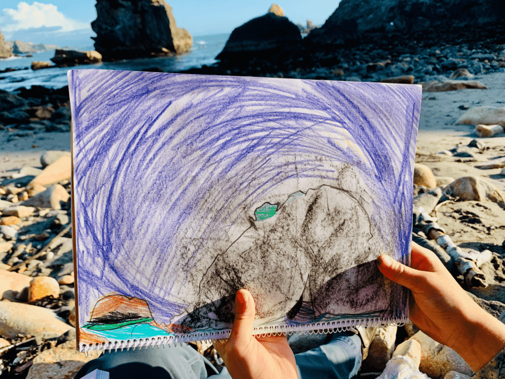 Kid holding up pastel nature sketch of rock art during Van Homeschool at Smith Rock State Park in Oregon