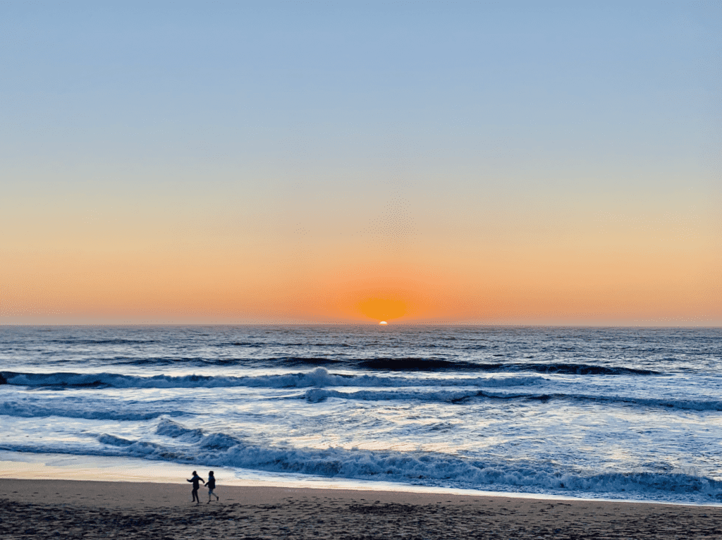 Ocean Sunset Prancing with orange glowing skies and blue crystal waves in the background