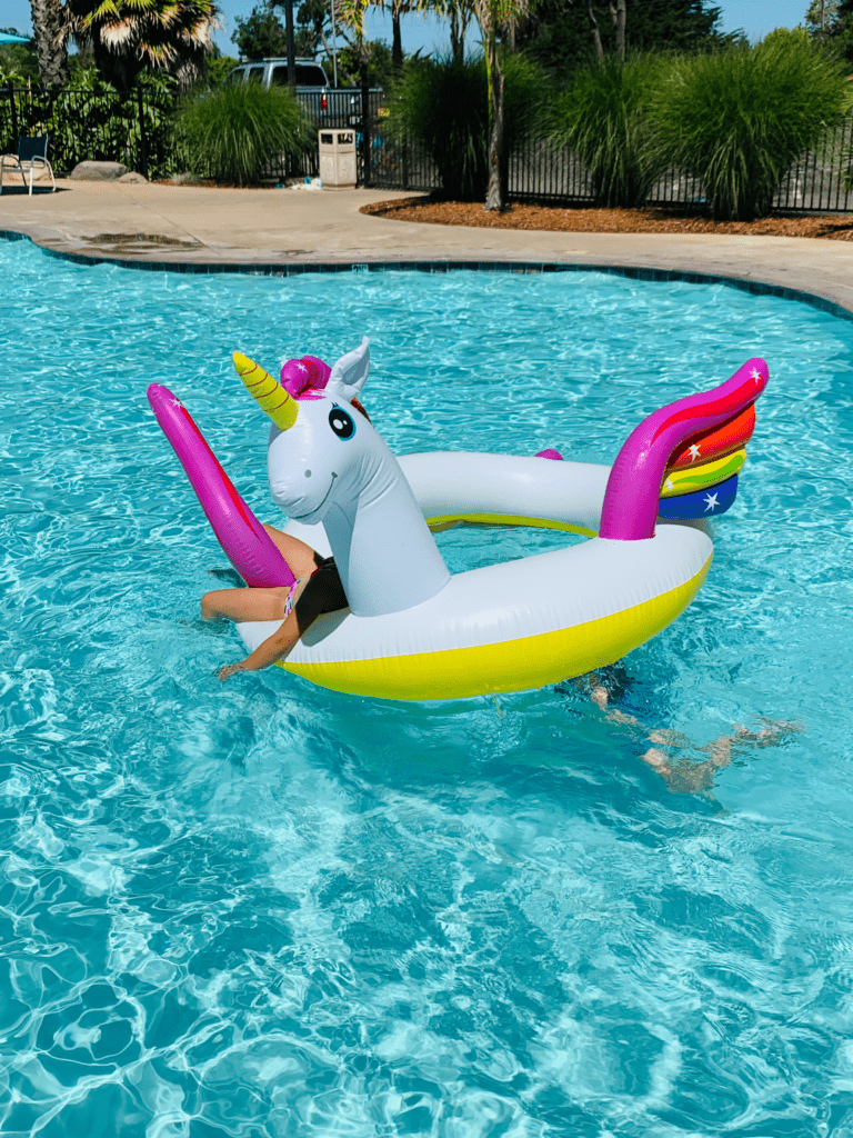 Lazy summer days in crystal clear blue pool with kids on a unicorn floatie at the Santa Cruz KOA