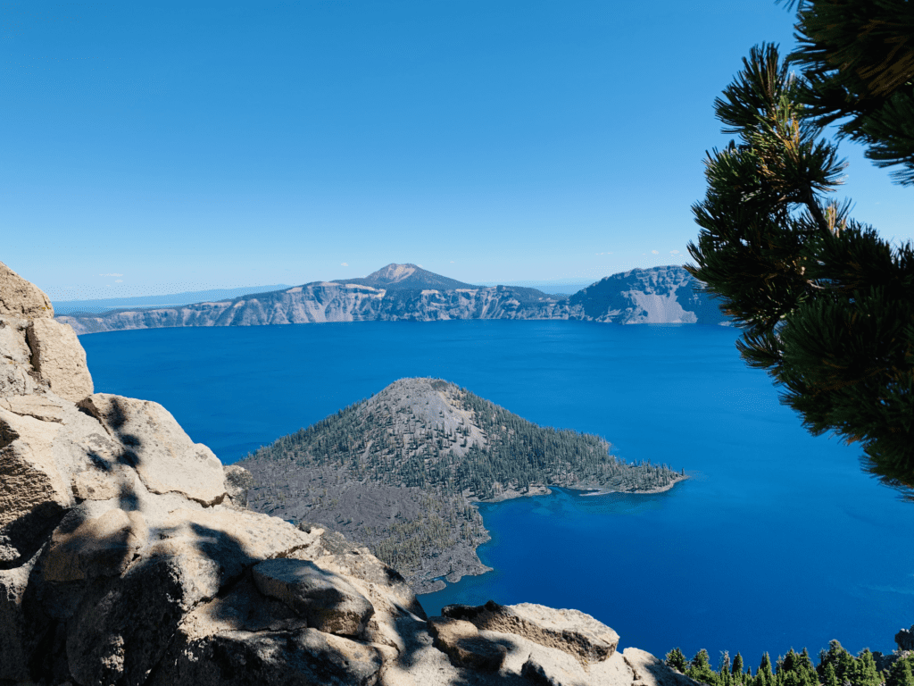 Wizard Island at Crater Lake on a clear skies day in Southern Oregon with deep blue lake and trees in background