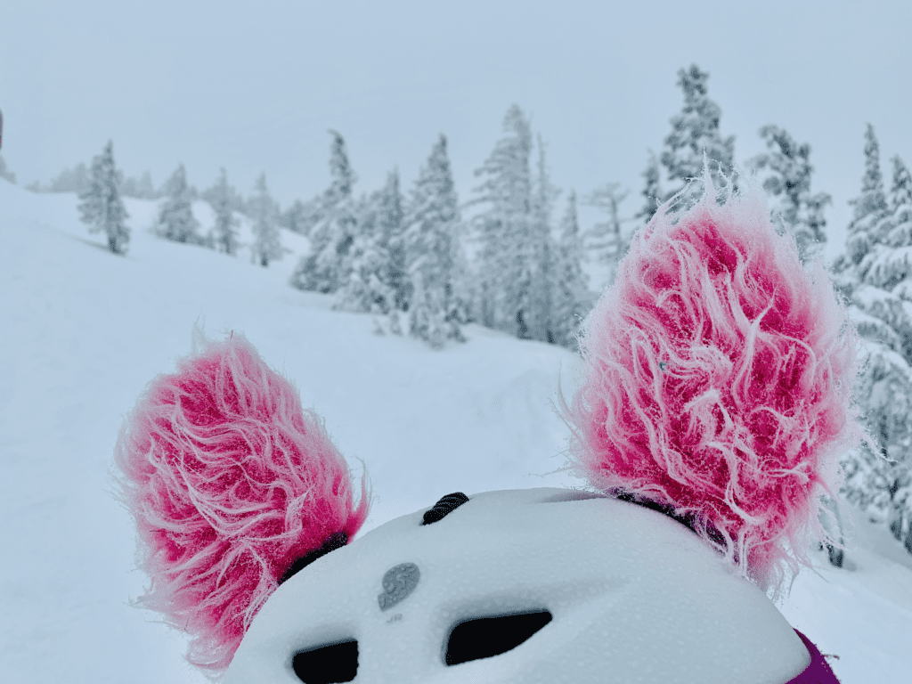 Mt Bachelor Valentines Storm Pink Puffs on younger kid ski helmet in Bend with hoarfrost conifers and white storm sky in the background