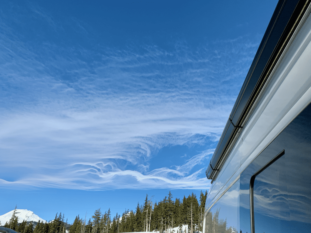 White Clouds with van parked at Mount Bachelor with brilliant blue skies and dancing cascade mountain clouds in the background