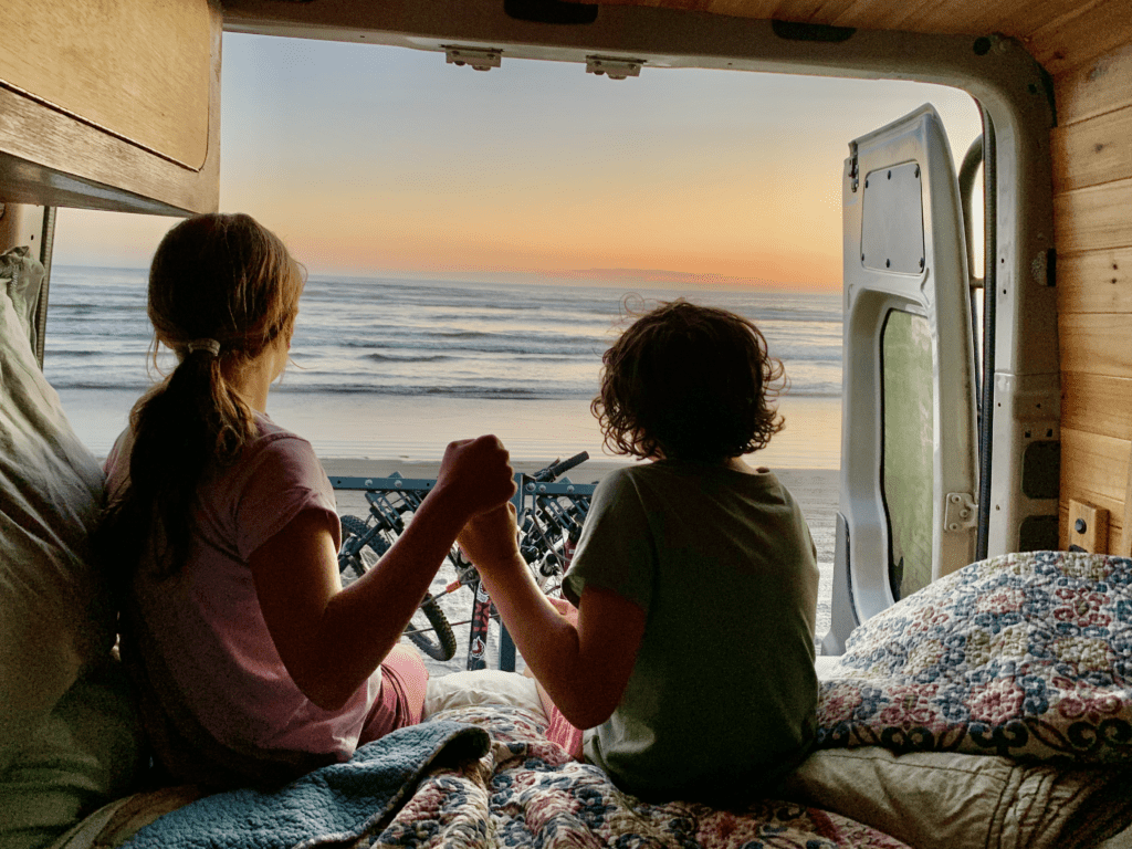 Fort Stevens State Beach on Oregon Coast at Sunset with daughters holding hands and the Pacific Ocean in the background