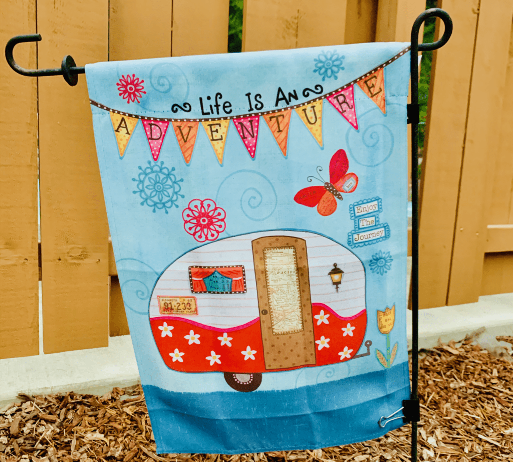 Life is an Adventure Enjoy the Journey sign with colorful RV and happy flag and butterflies