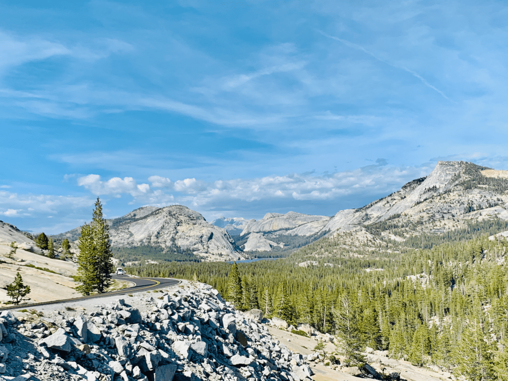 Road to Tuolumne Meadows in Yosemite National Park with fluffy clouds dancing over the the Sierra Nevada in the background