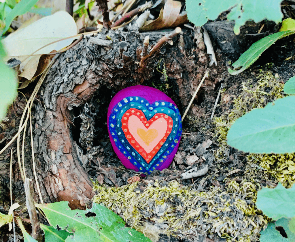 Rock art heart with layers of colorful dots and gold heart in middle wrapped inside a tree with leaves surrounding