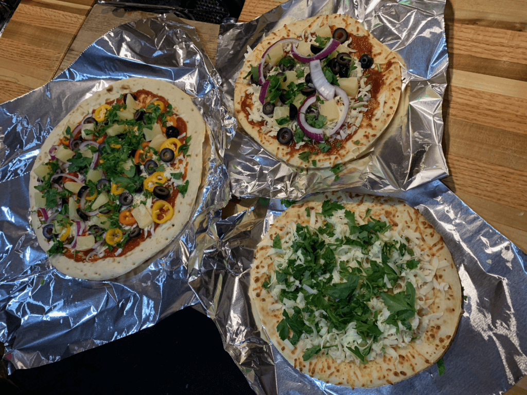 Colorful vegetable rich mini pizzas on tinfoil with the van kitchen in the background