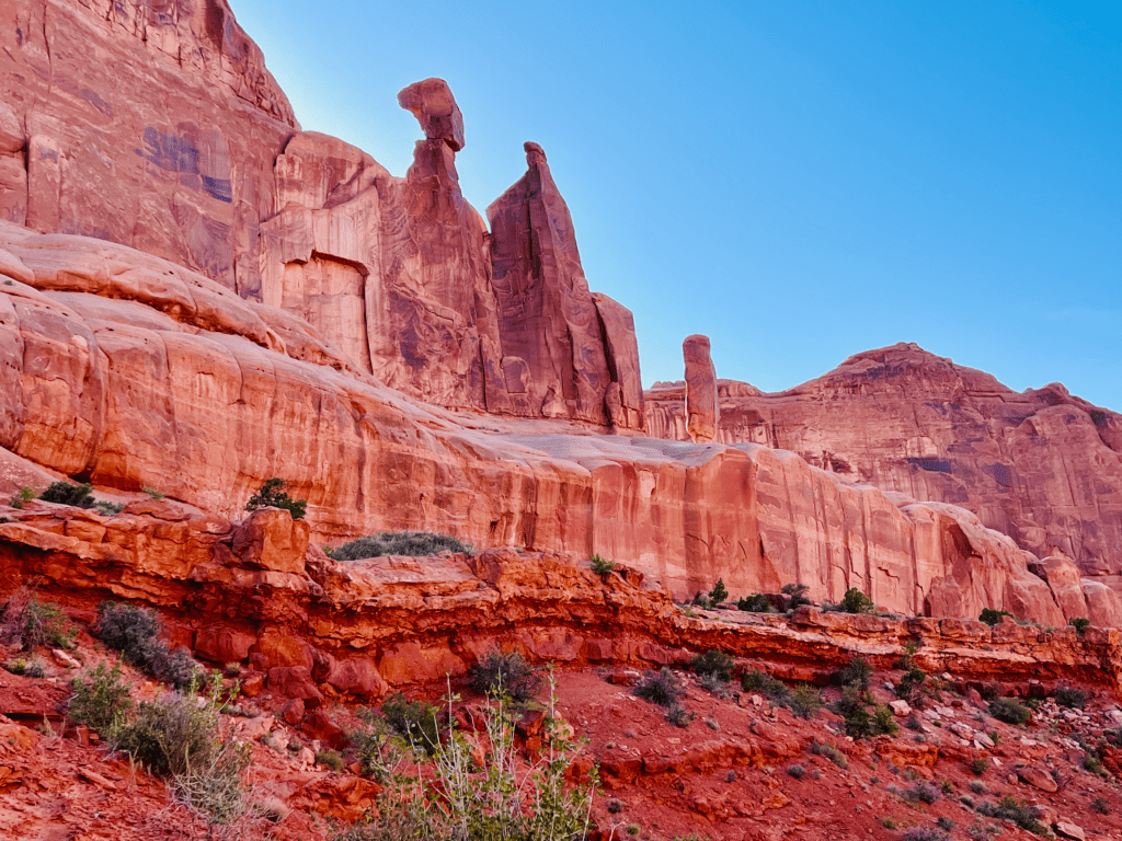 Egyptian Rock Goddesses at Arches with towering redwall limestone and clear blue skies in the background