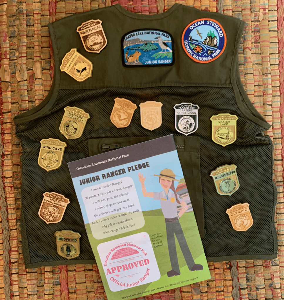 Junior Ranger Vest with Junior Ranger badges and Junior Ranger pledge on back of a Junior Ranger booklet