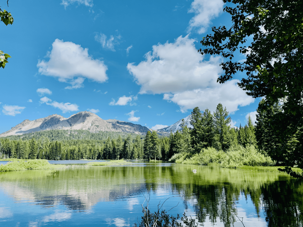 Reflections at Manzanita Lake at Lassen National Park with bright blue water and skies and green trees reflected in the background