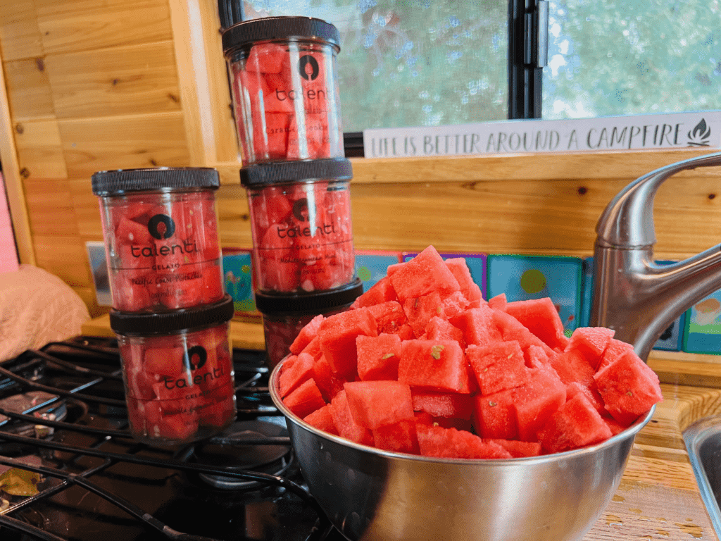 Juicy red van watermelon delight with talent jars and giant watermelon bowl with life is better around a campfire sign in the background