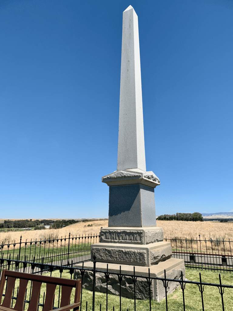 Whitman Memorial at Whitman Mission National Historic Site with rolling grassy hills and blue skies in the background