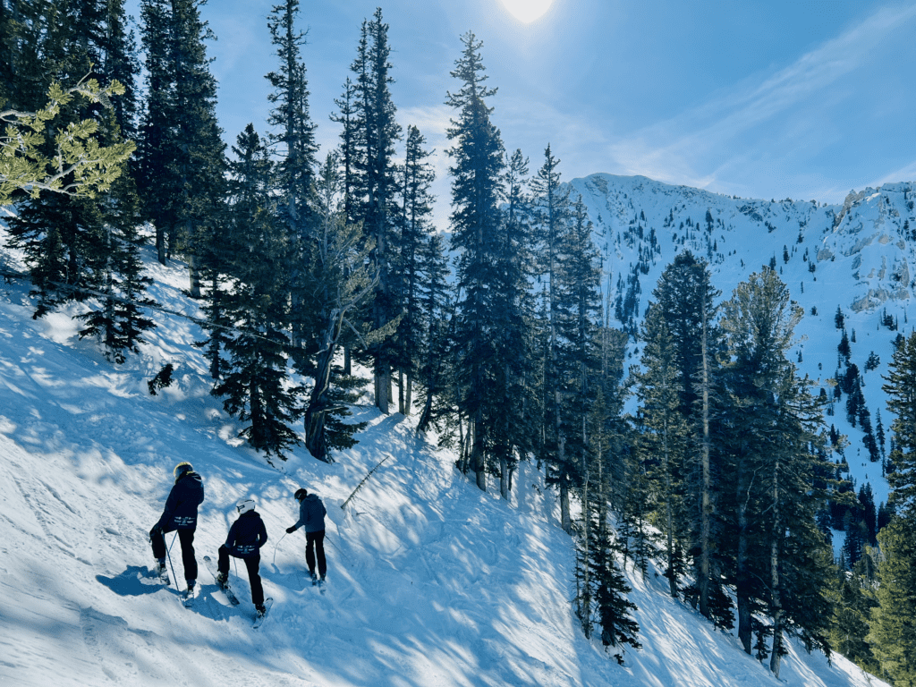 Solitude Ski Resort in Utah skiers heading into Honeycomb Canyon with Wasatch Mountains and blue skies in the background