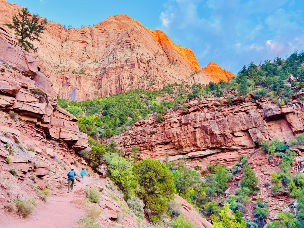 Kids and Dad hiking On Trail to The Watchman with red rock mountains in the background