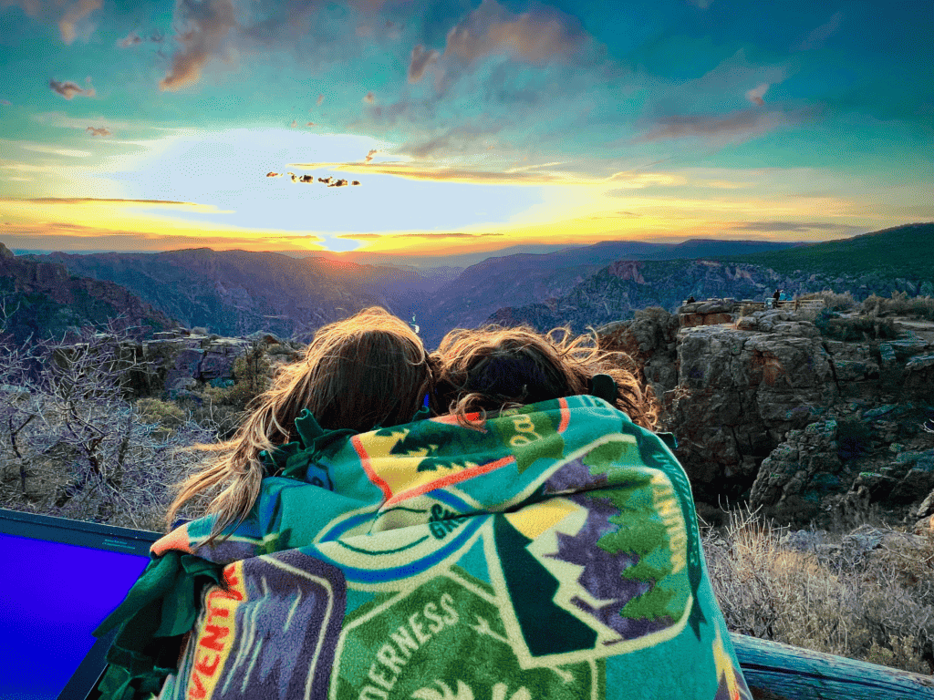 Sisterly Love at Black Canyon of the Gunnison National Park with sisters holding each other in a national park explore nature wilderness adventure blanket with canyon Sunset and black rocks in the background